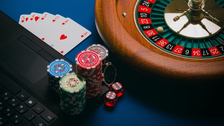 gambling chips next to a keyboard and a roulette wheel